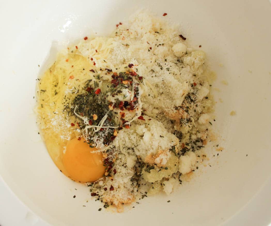 All of the ingredients for cauliflower pizza crust in a mixing bowl.