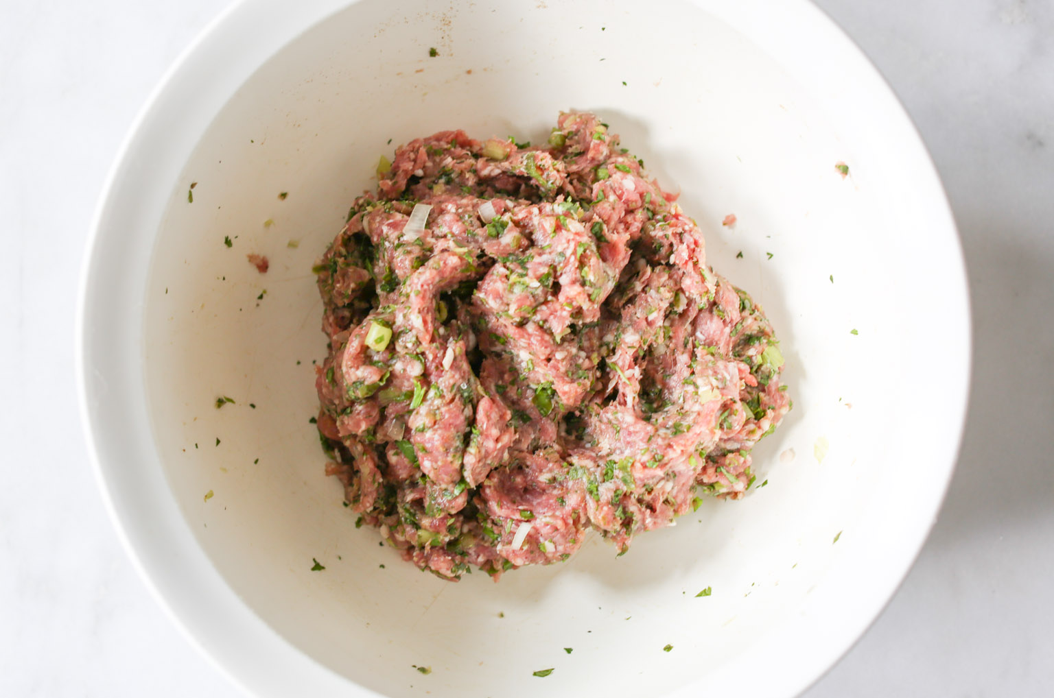 Overhead shots of all ingredients for spiced lamb meatballs mixed together and ready to be rolled into meatballs.