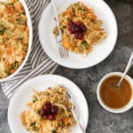 Overhead view of two portions of Thanksgiving Quinoa Bake topped with cranberry sauce with the casserole dish peeking in from the left side.
